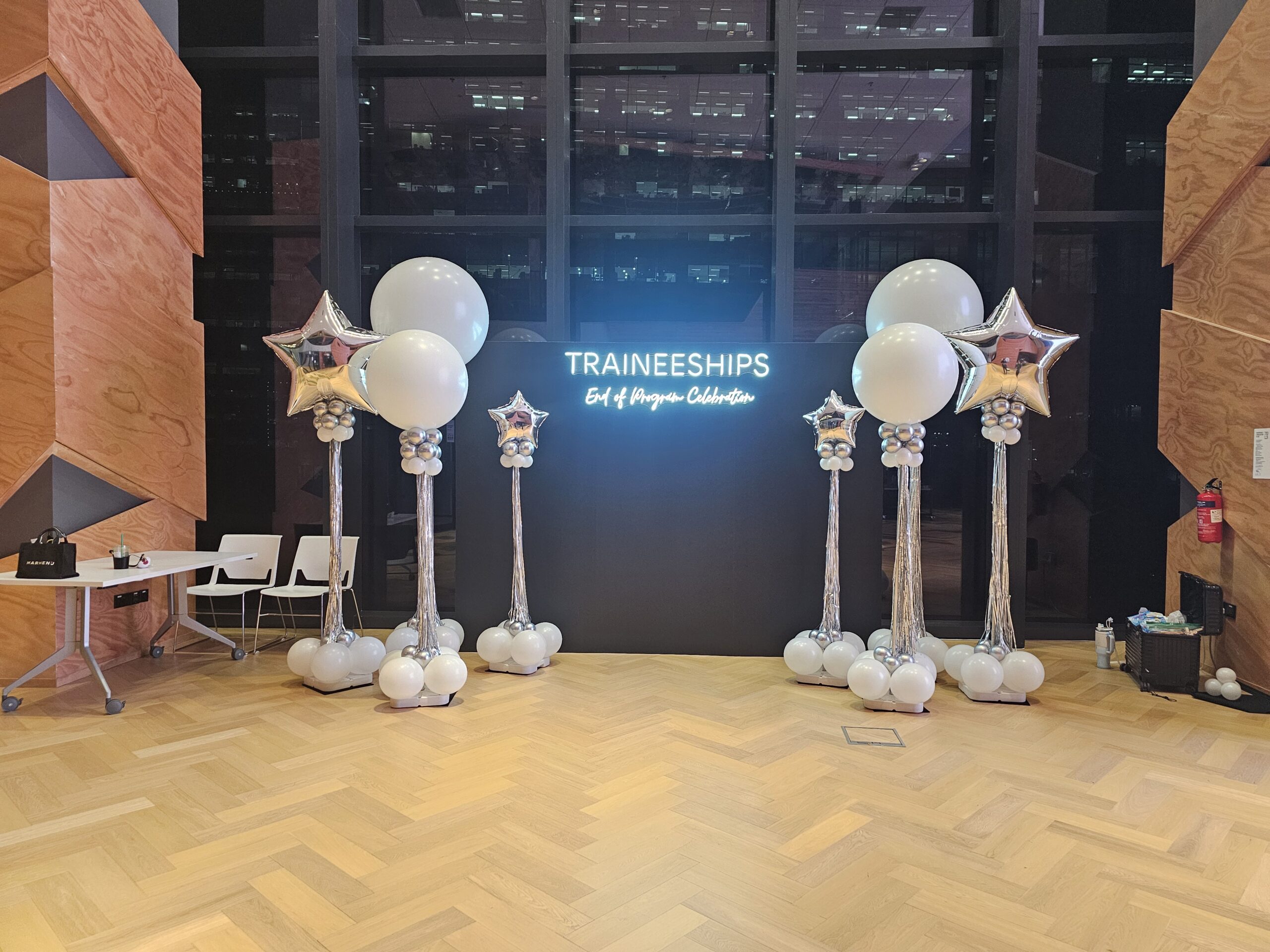 Silver balloon columns Singapore lining a sleek black stage backdrop for a corporate celebration