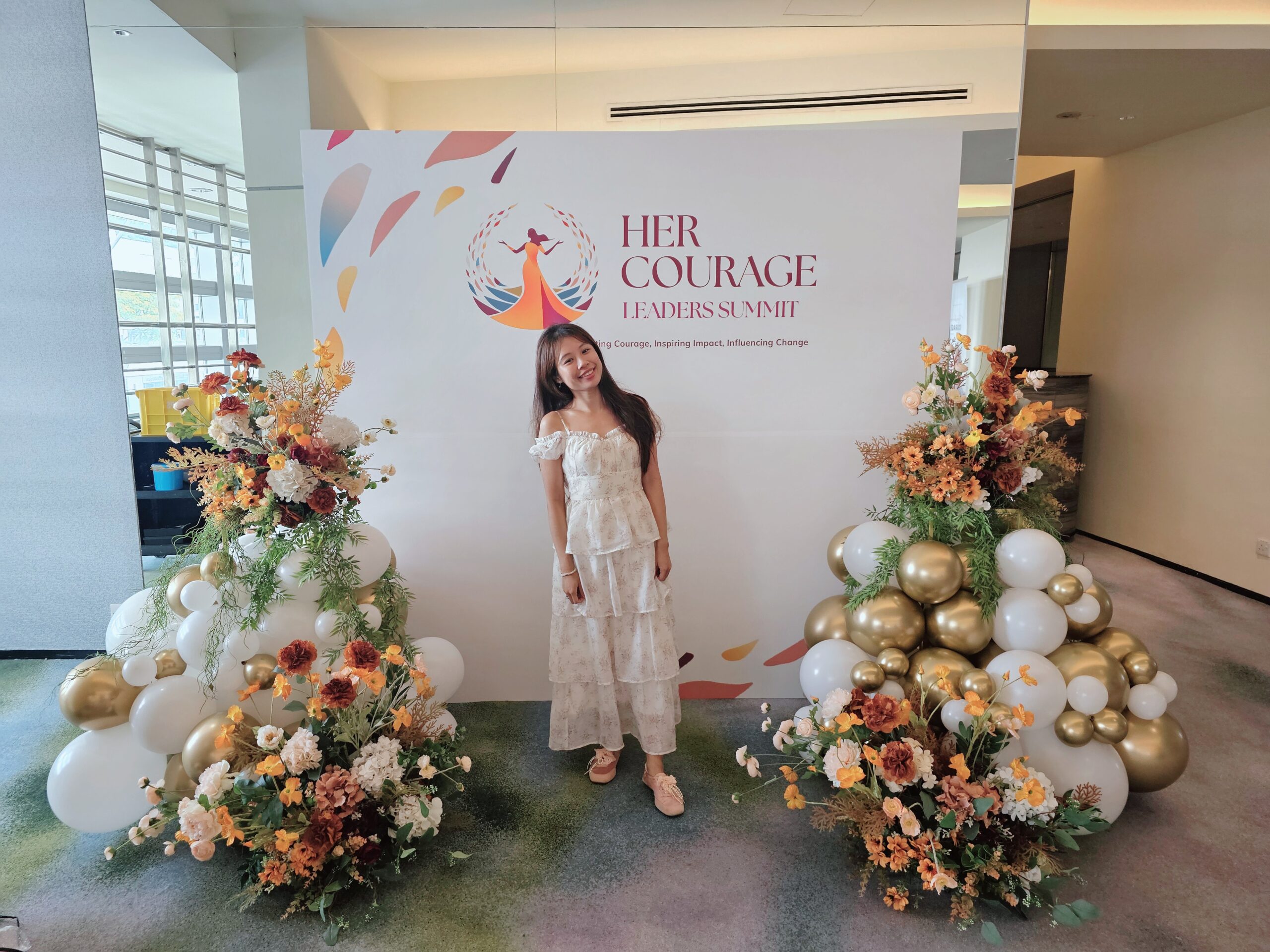 Smiling attendee beside floral event balloon decoration Singapore corporate summit